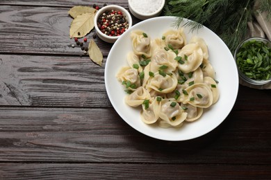 Photo of Delicious pelmeni with green onion served on wooden table, flat lay. Space for text