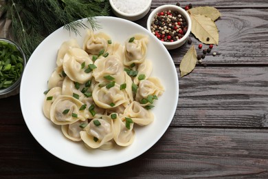 Photo of Delicious pelmeni with green onion served on wooden table, flat lay