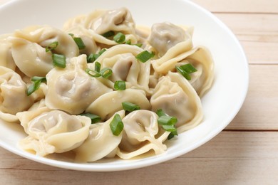 Delicious pelmeni with green onion on white wooden table, closeup