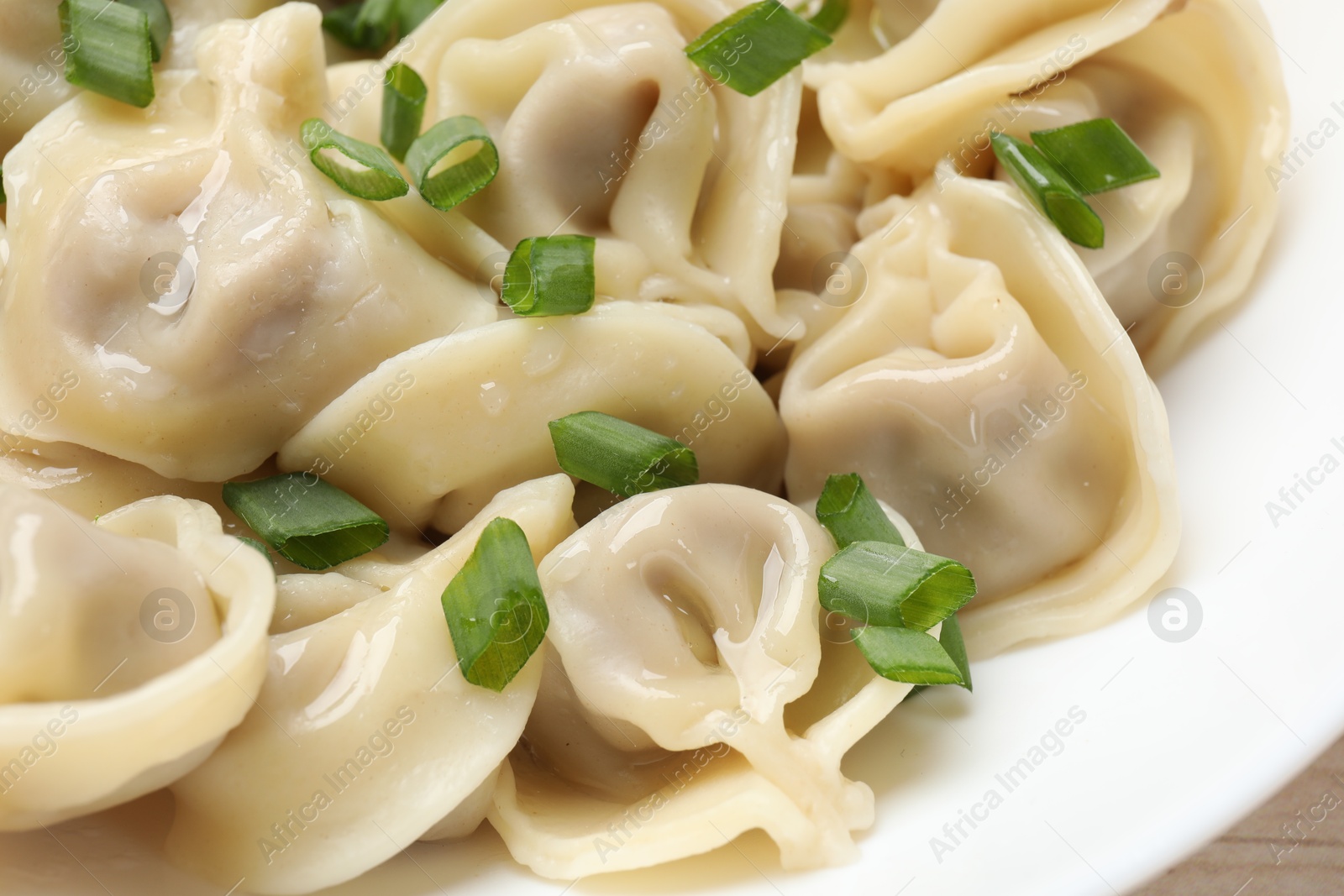 Photo of Delicious pelmeni with green onion on plate, closeup