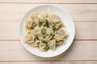 Delicious pelmeni with green onion on white wooden table, top view