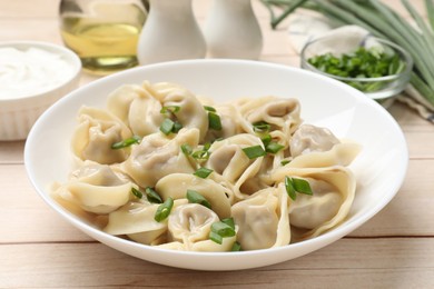 Photo of Delicious pelmeni with green onion served on white wooden table, closeup