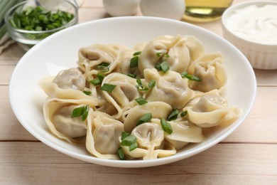 Photo of Delicious pelmeni with green onion served on white wooden table, closeup