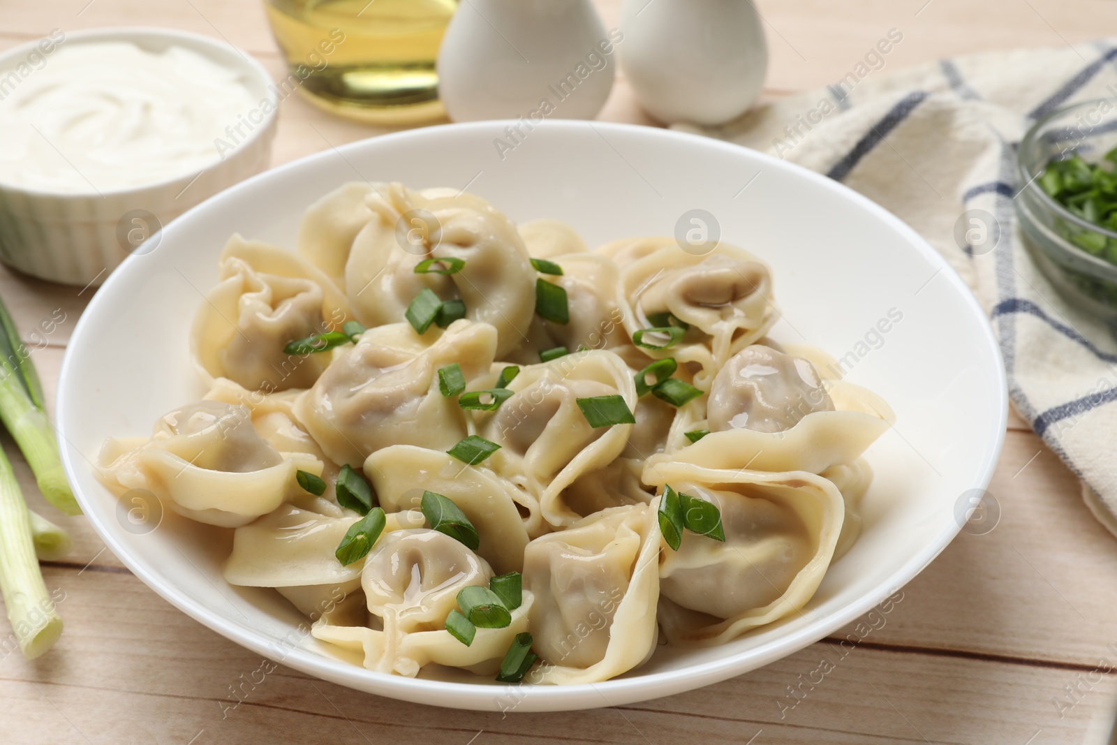 Photo of Delicious pelmeni with green onion served on white wooden table, closeup