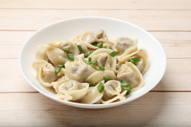 Delicious pelmeni with green onion on white wooden table