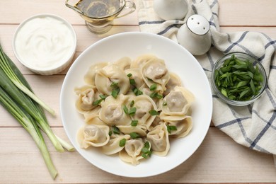 Photo of Delicious pelmeni with green onion served on white wooden table, flat lay