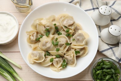 Photo of Delicious pelmeni with green onion served on white wooden table, flat lay