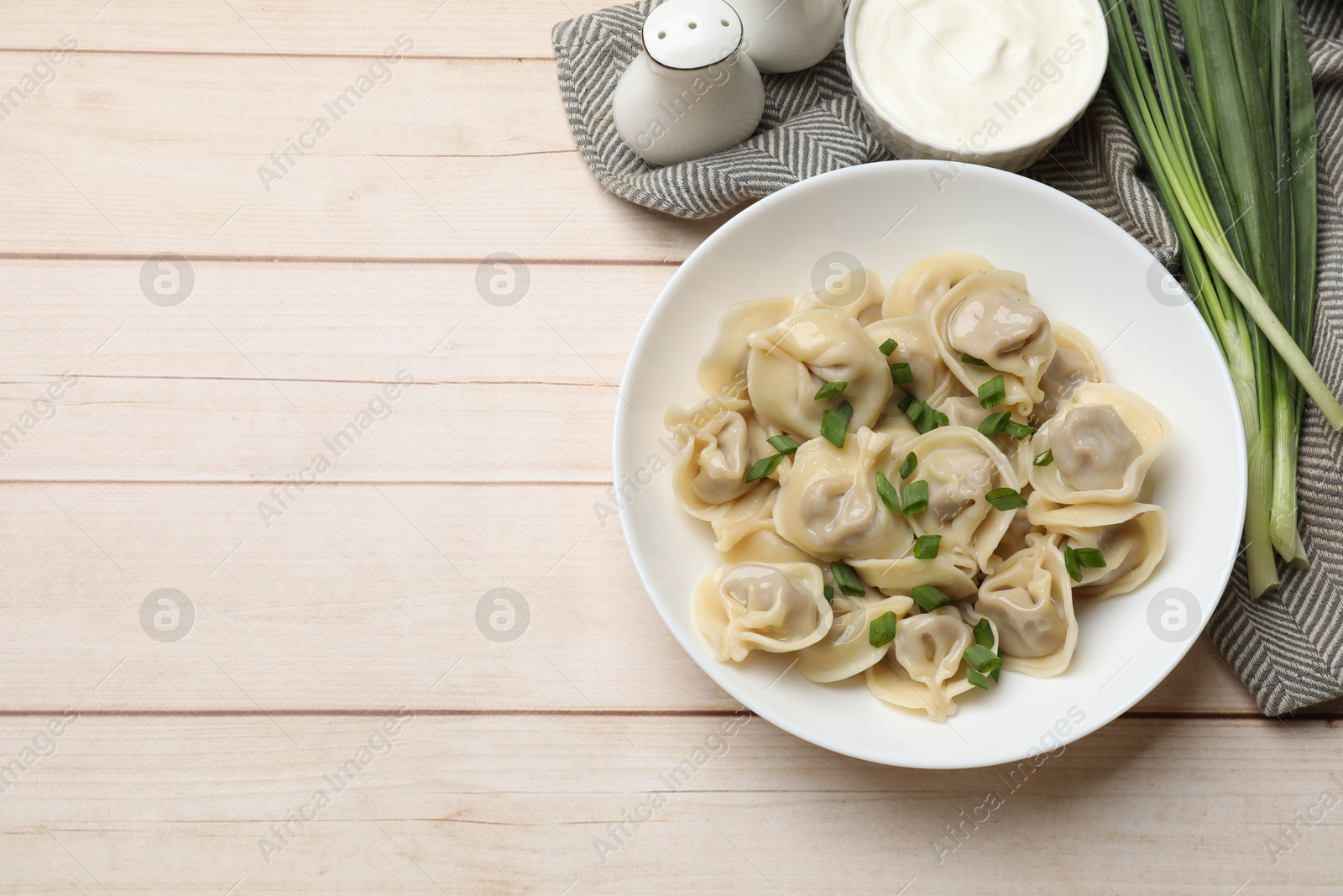 Photo of Delicious pelmeni with green onion served on white wooden table, flat lay. Space for text