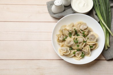 Delicious pelmeni with green onion served on white wooden table, flat lay. Space for text