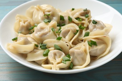 Photo of Delicious pelmeni with green onion on blue wooden table, closeup