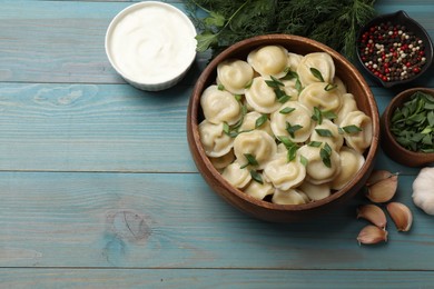 Photo of Delicious pelmeni with green onion served on light blue wooden table, flat lay. Space for text