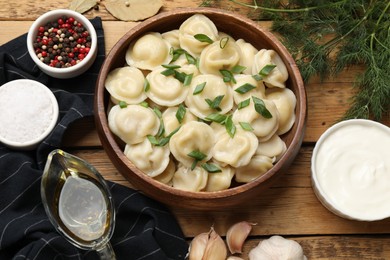 Photo of Delicious pelmeni with green onion served on wooden table, flat lay