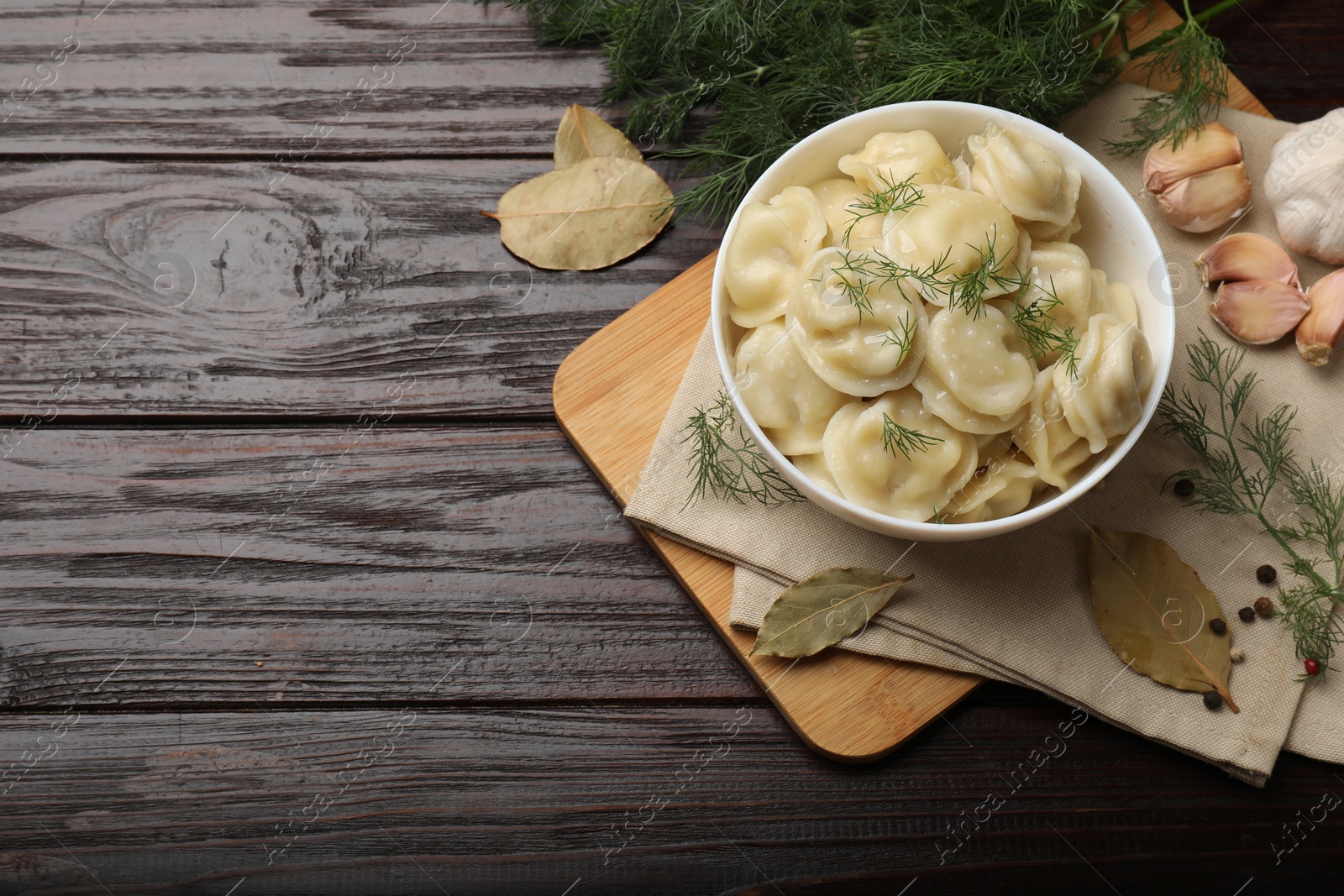 Photo of Delicious pelmeni with dill served on wooden table, flat lay. Space for text