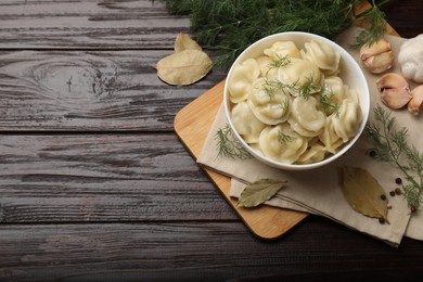 Photo of Delicious pelmeni with dill served on wooden table, flat lay. Space for text