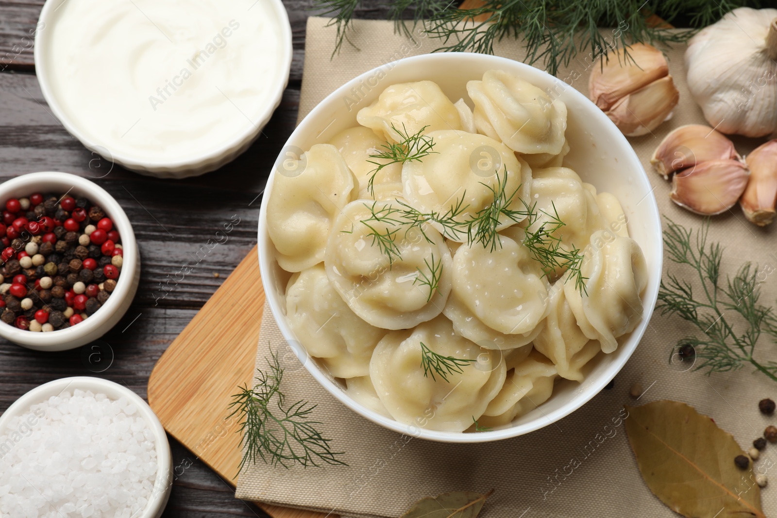 Photo of Delicious pelmeni with dill served on wooden table, flat lay