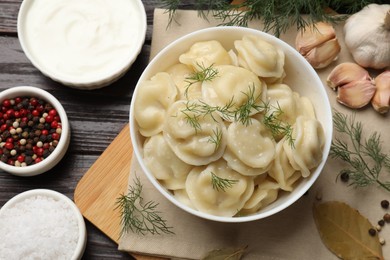 Delicious pelmeni with dill served on wooden table, flat lay