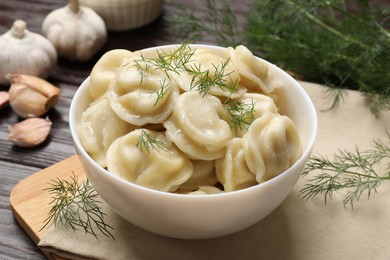 Photo of Delicious pelmeni with dill on wooden table, closeup