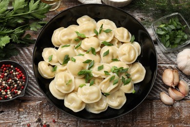 Photo of Delicious pelmeni with green onion served on wooden table, flat lay