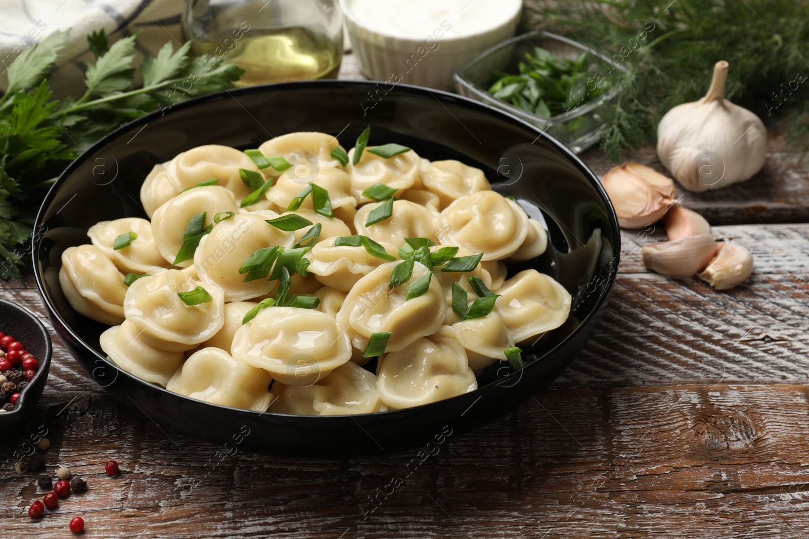 Photo of Delicious pelmeni with green onion served on wooden table, closeup