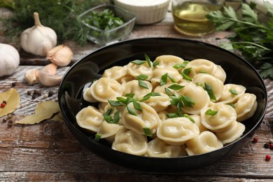 Delicious pelmeni with green onion served on wooden table, closeup