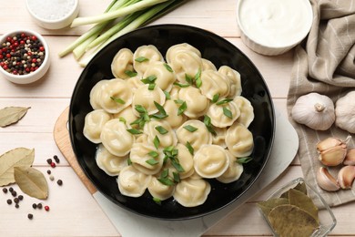 Delicious pelmeni with green onion served on wooden table, flat lay