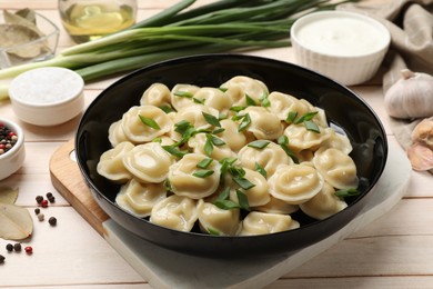 Photo of Delicious pelmeni with green onion served on wooden table, closeup