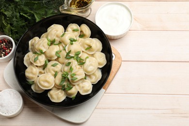 Photo of Delicious pelmeni with green onion served on wooden table, flat lay. Space for text