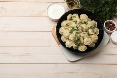 Photo of Delicious pelmeni with green onion served on wooden table, flat lay. Space for text