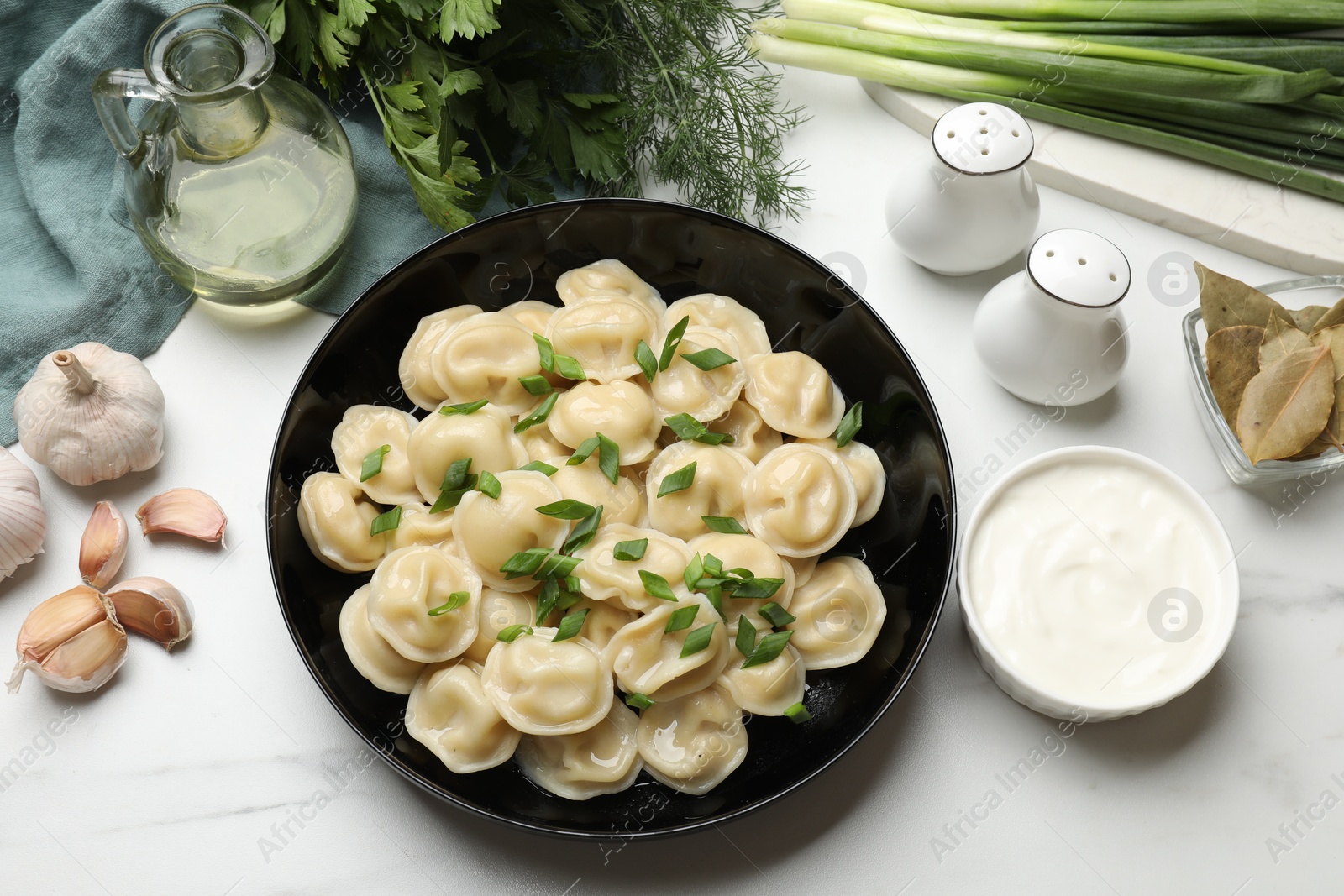 Photo of Delicious pelmeni with green onion served on light table, flat lay