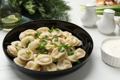 Photo of Delicious pelmeni with green onion served on light table, closeup