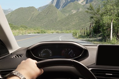 Image of Man driving car on mountain road, first-person view