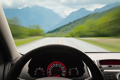 Image of Car driving on mountain road at high speed, view from driver's seat. Motion blur effect