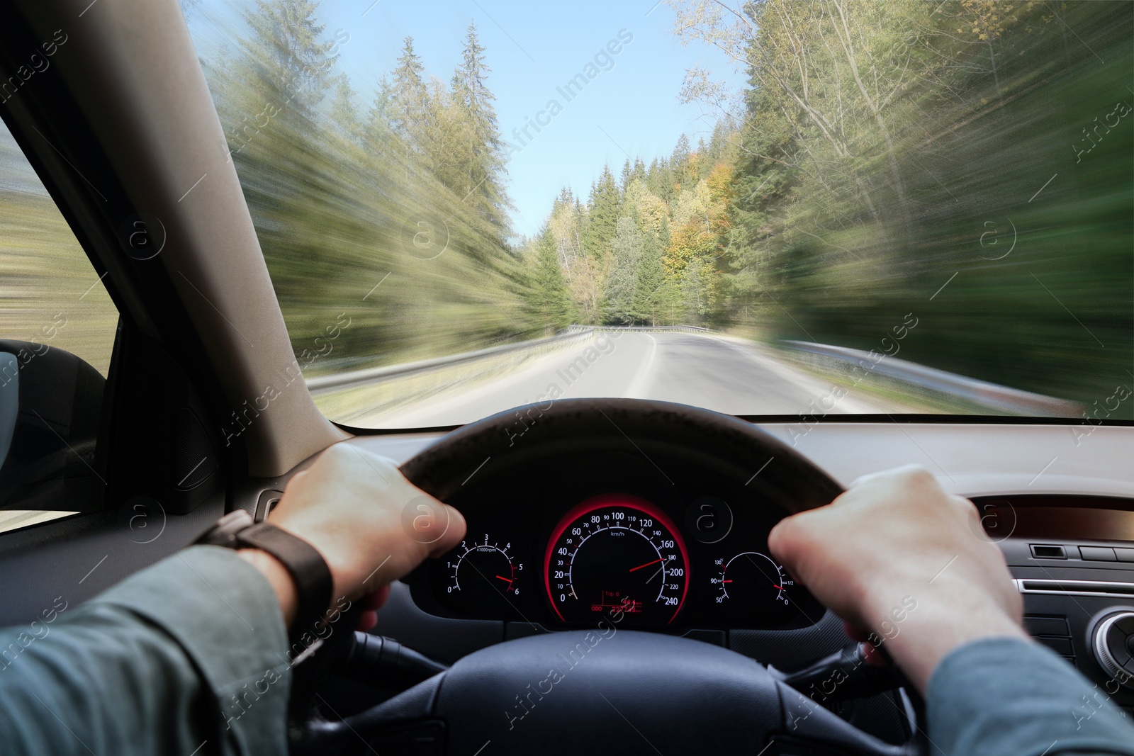 Image of Man driving car on empty road at high speed, first-person view. Motion blur effect