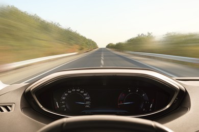 Image of Car driving on empty road at high speed, view from driver's seat. Motion blur effect