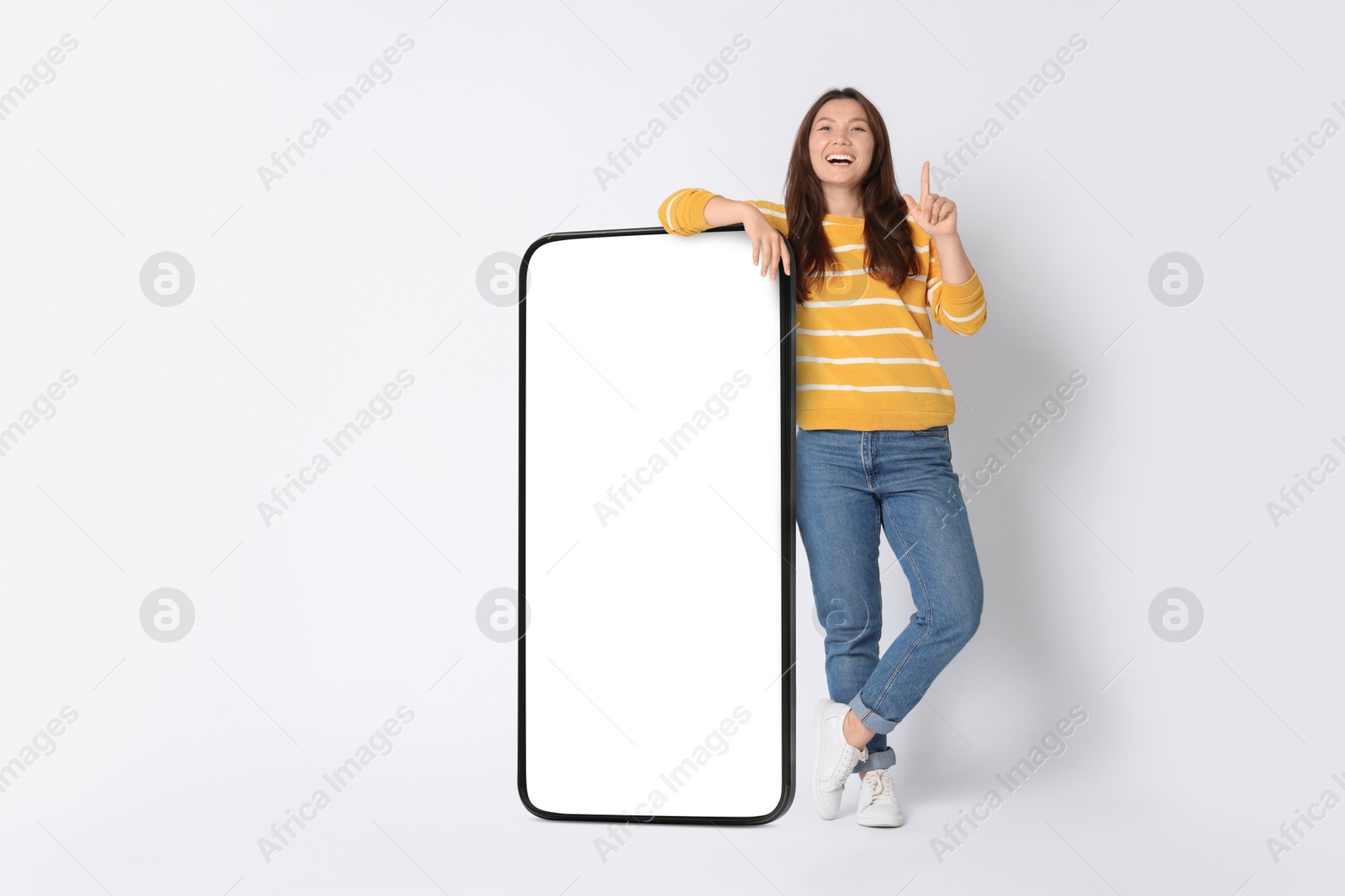 Image of Happy smiling woman and big mobile phone with blank screen on white background. Mockup for design