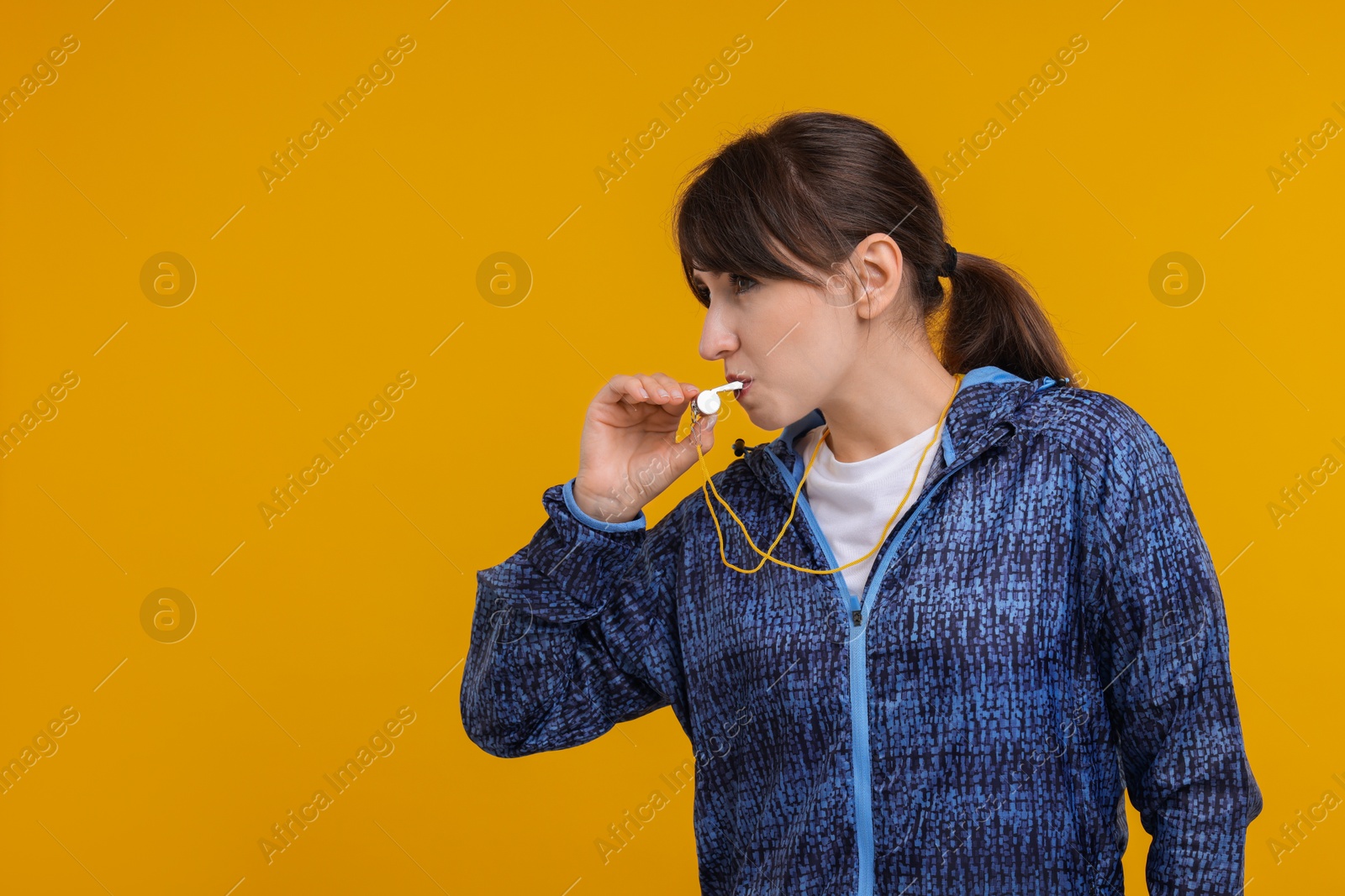 Photo of Woman blowing whistle on orange background, space for text