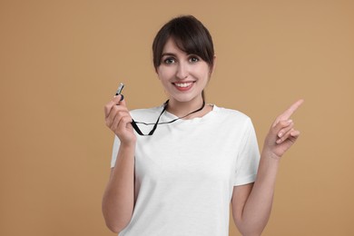 Happy woman with whistle on beige background