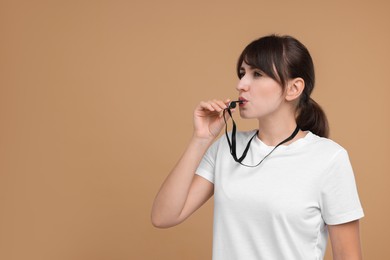 Photo of Woman blowing whistle on beige background, space for text