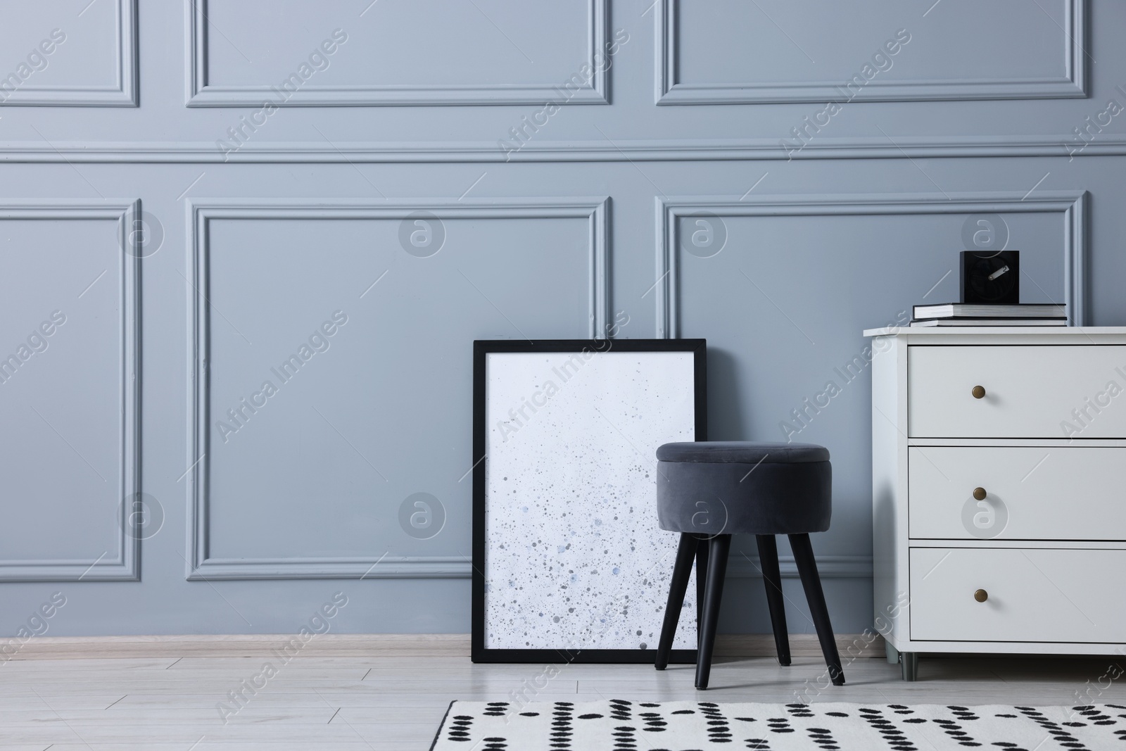 Photo of Stylish interior with stool and chest of drawers near light grey wall, space for text