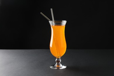 Photo of Tasty refreshing drink with straws in glass on grey table