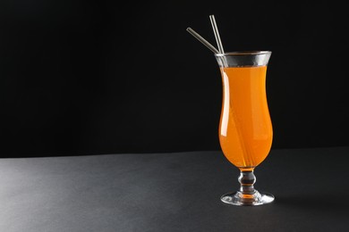 Photo of Tasty refreshing drink with straws in glass on grey table, space for text