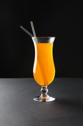 Photo of Tasty refreshing drink with straws in glass on grey table