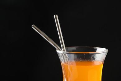 Photo of Tasty refreshing drink with straws in glass on black background, closeup