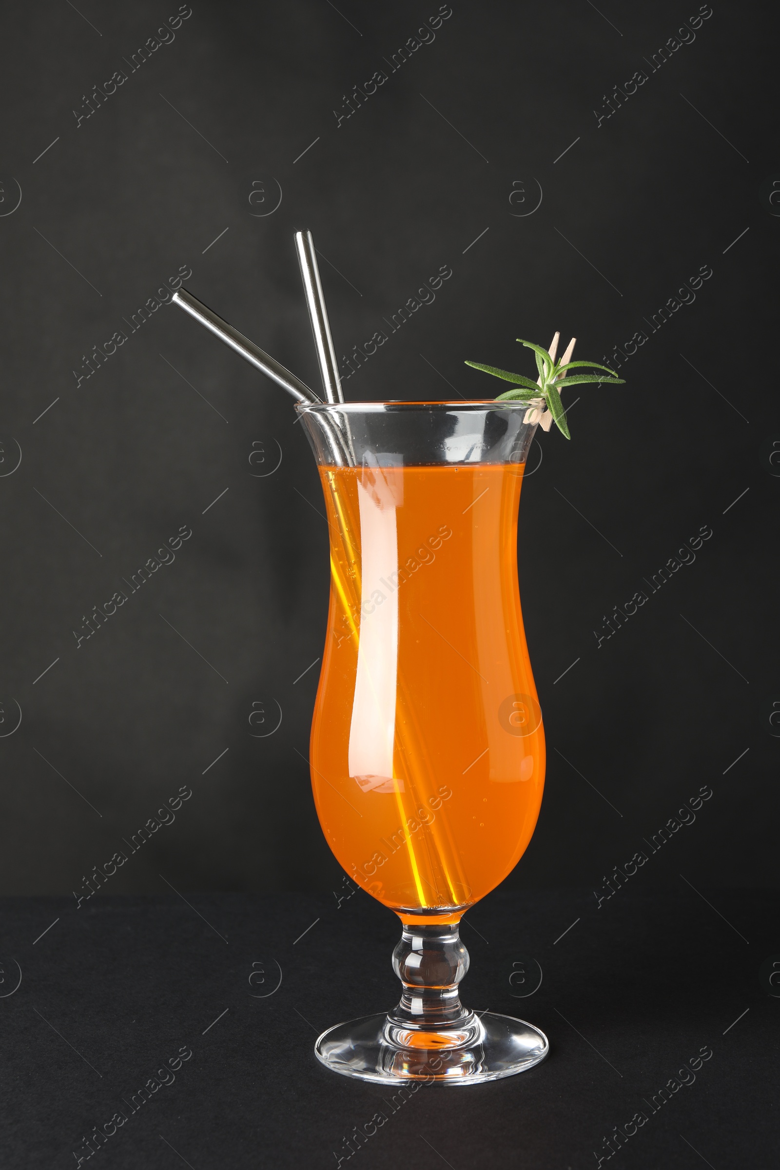 Photo of Tasty refreshing drink with straws in glass on grey background