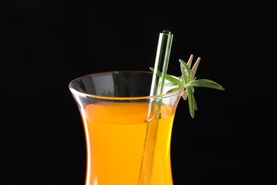 Photo of Tasty refreshing drink with straw in glass on black background, closeup