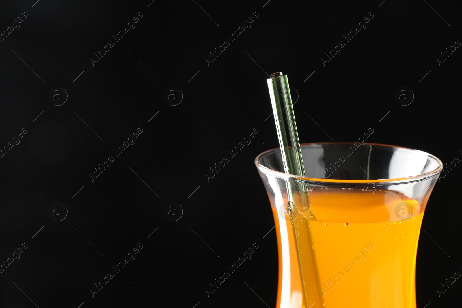 Photo of Tasty refreshing drink with straw in glass on black background, closeup. Space for text