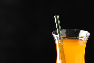 Photo of Tasty refreshing drink with straw in glass on black background, closeup. Space for text