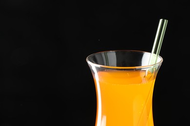 Photo of Tasty refreshing drink with straw in glass on black background, closeup. Space for text