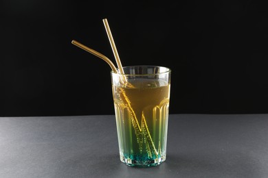 Tasty refreshing drink with straws in glass on grey table