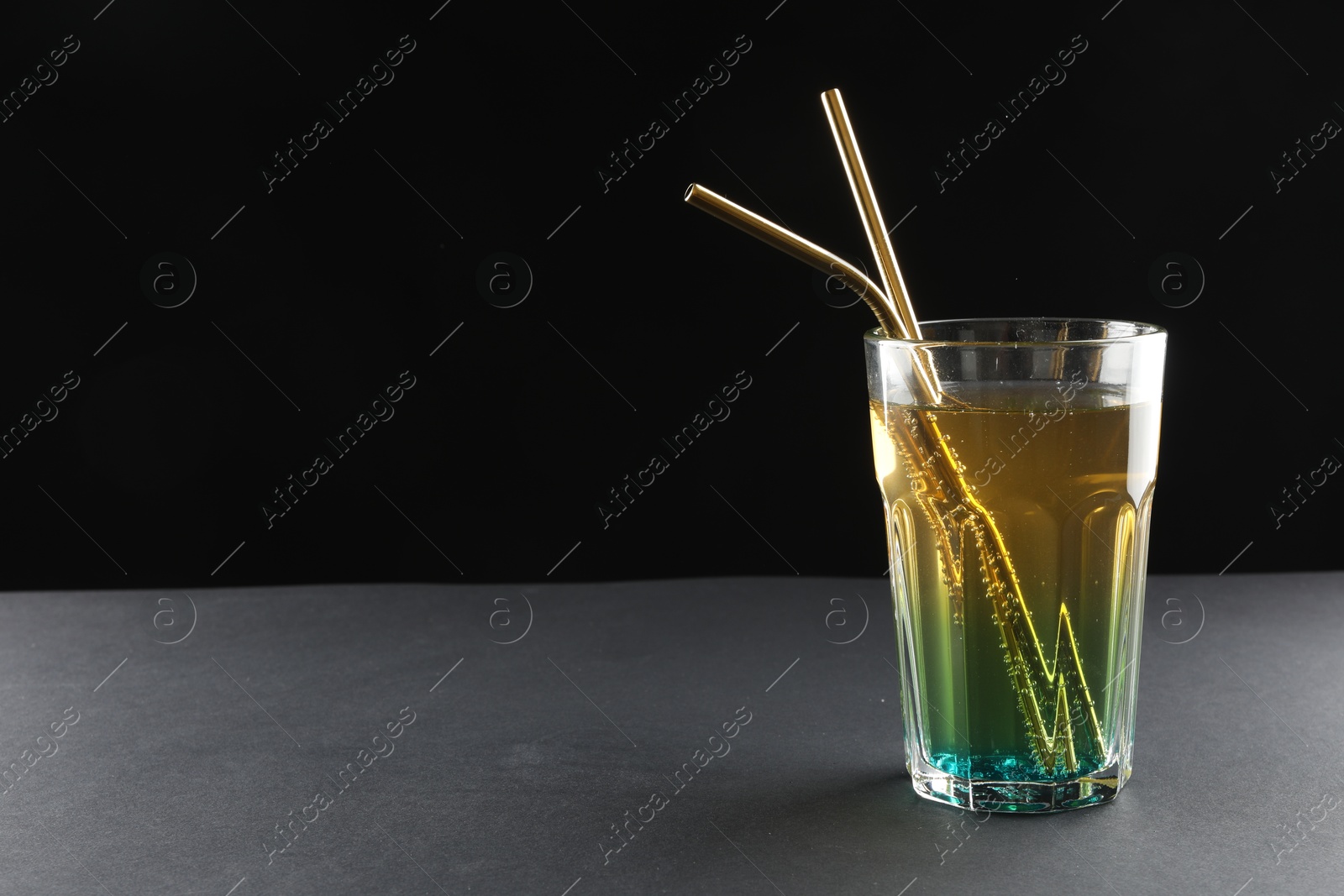 Photo of Tasty refreshing drink with straws in glass on grey table, space for text